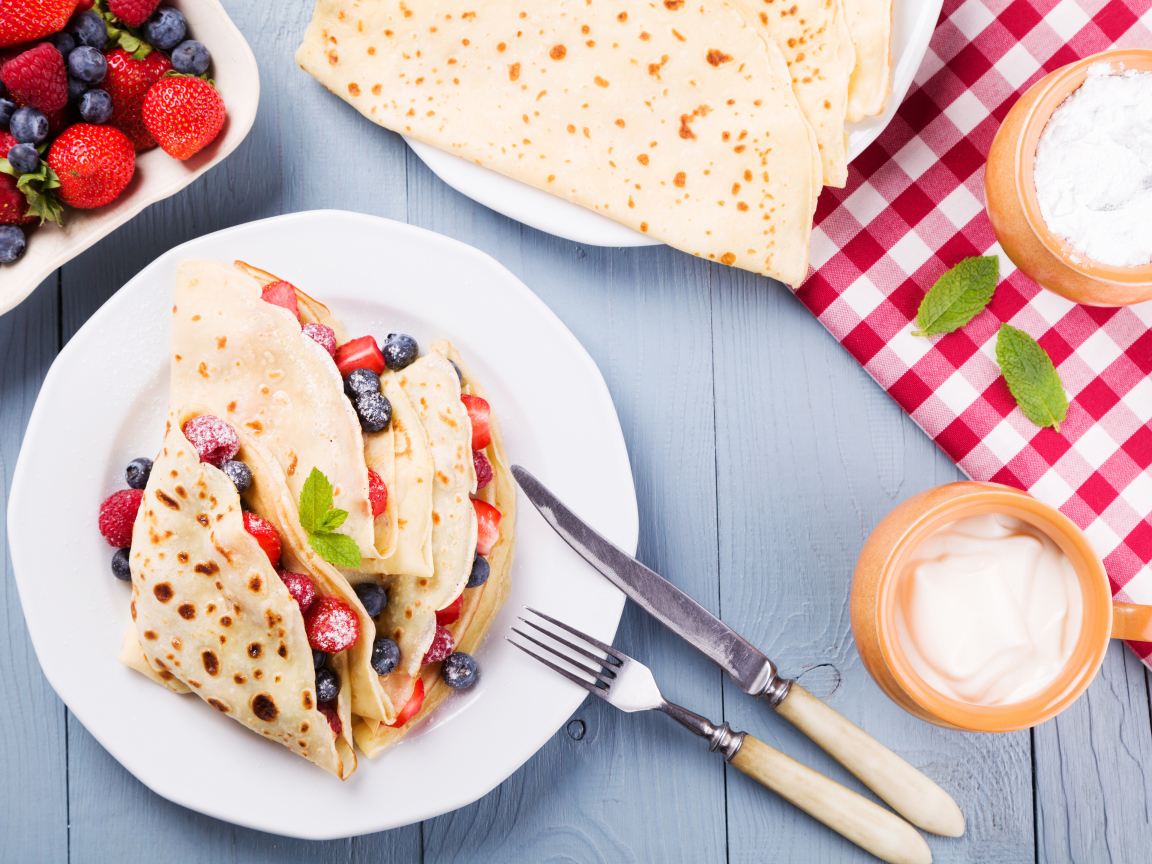 Аппетитные блинчики с ягодами на белой тарелке 