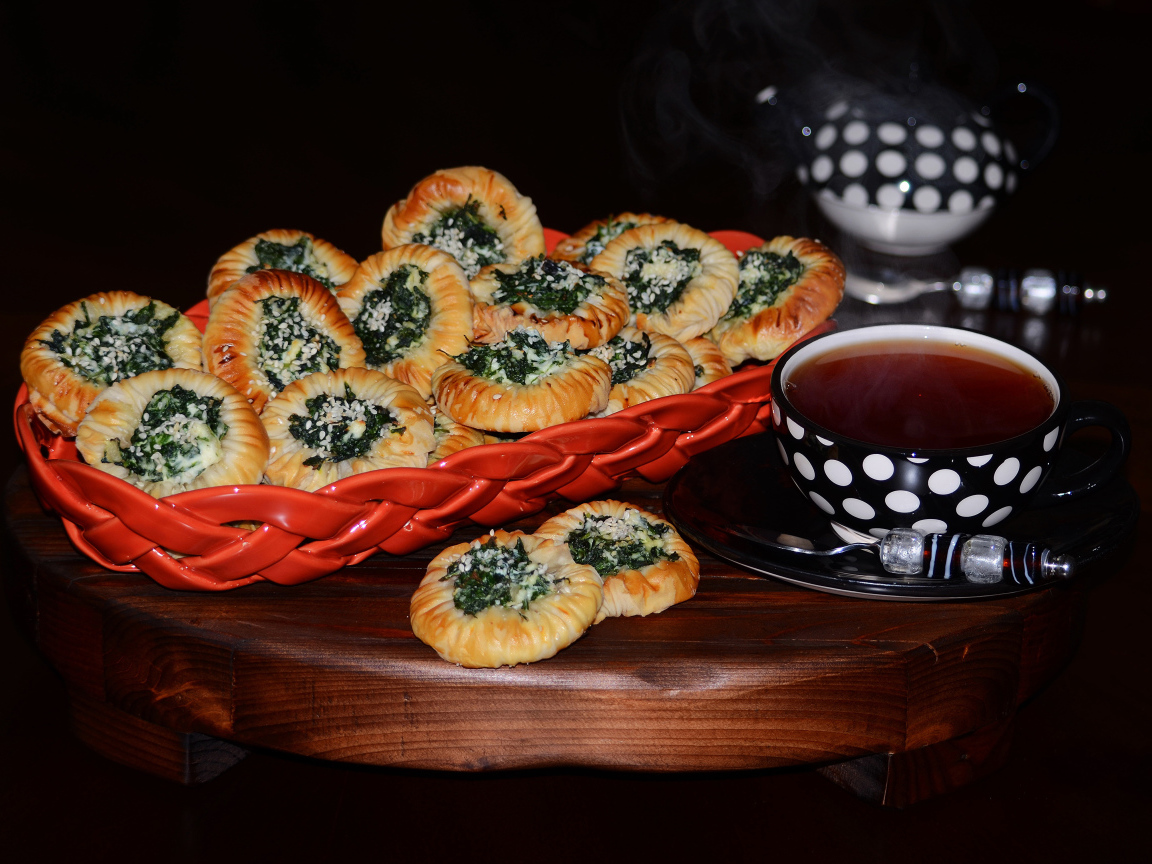 Булочки с зеленью и горячим чаем на черном фоне