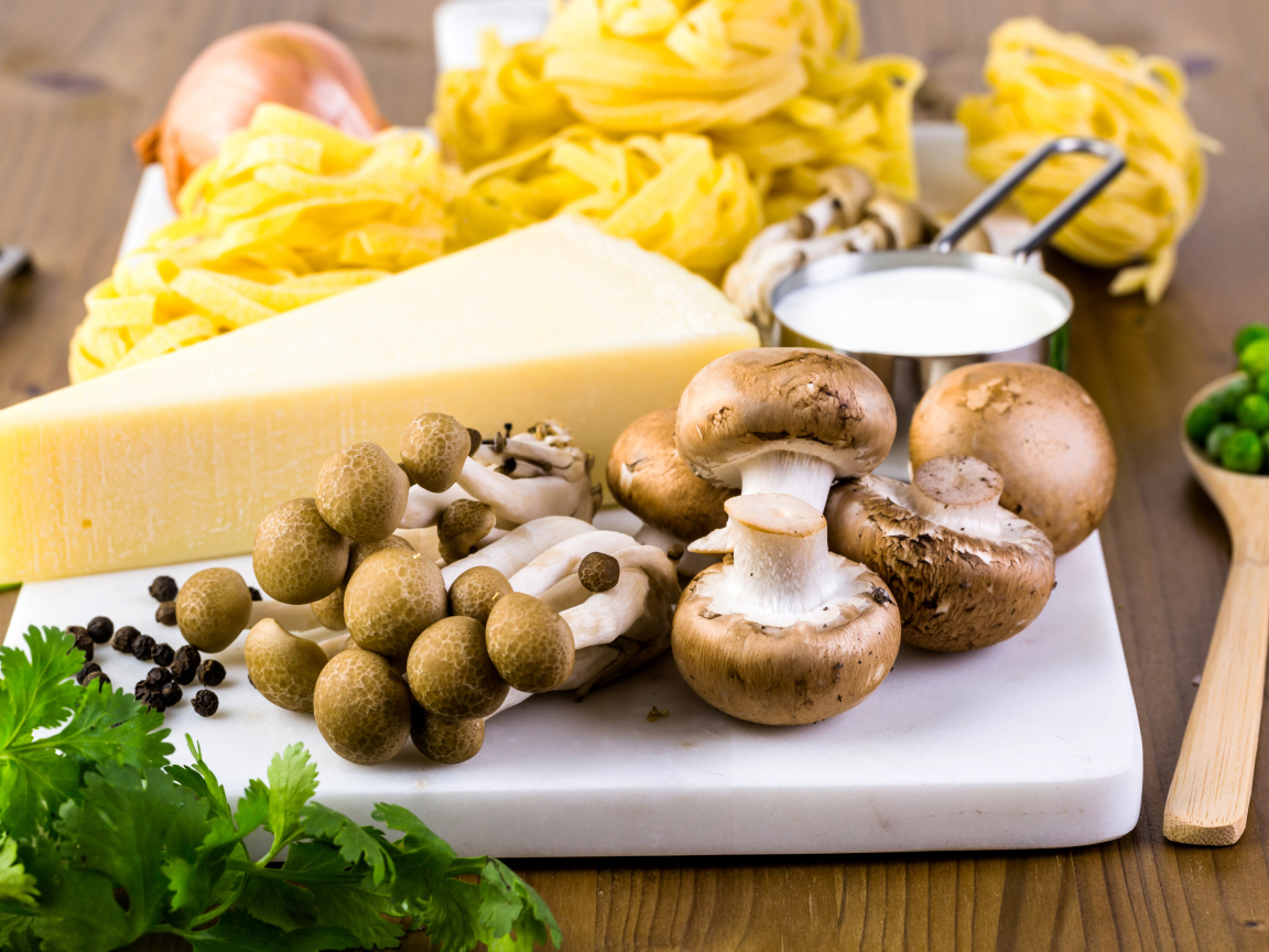 Грибы на разделочной доске с сыром, макаронами и зеленью