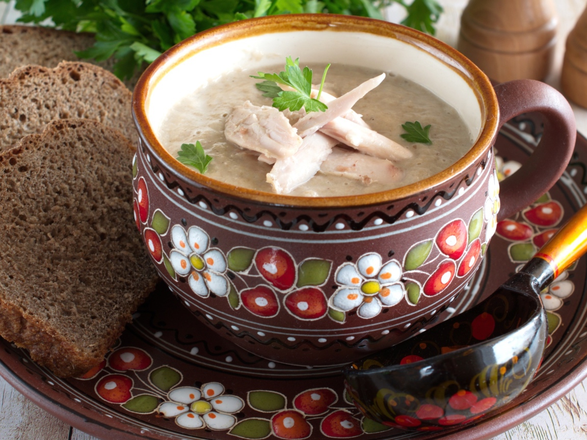 Суп с курицей в красивой тарелке на столе с черным хлебом