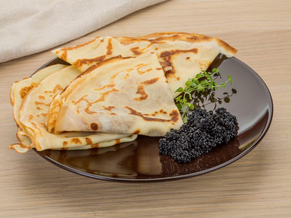 Тонкие блины на тарелке с черной икрой