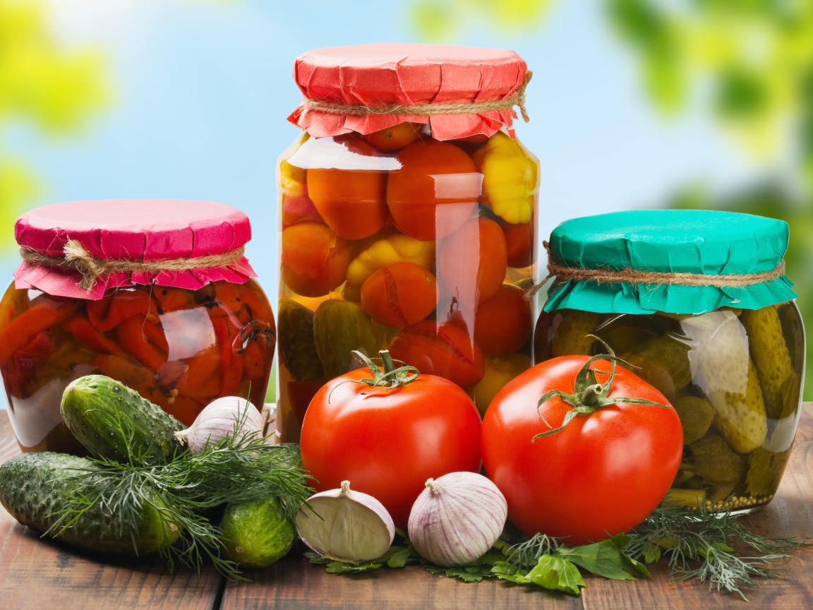 Три банки с заготовками из огурцов, помидоров и сладкого перца