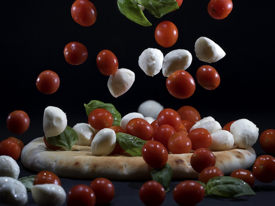 Помидоры и сыр Моцарелла падают на пиццу 