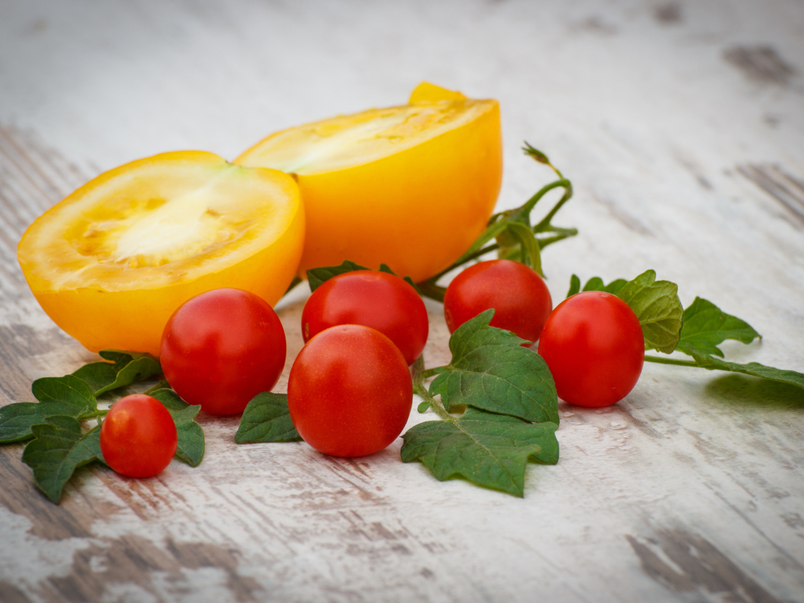 Желтые и красные помидоры на деревянной доске