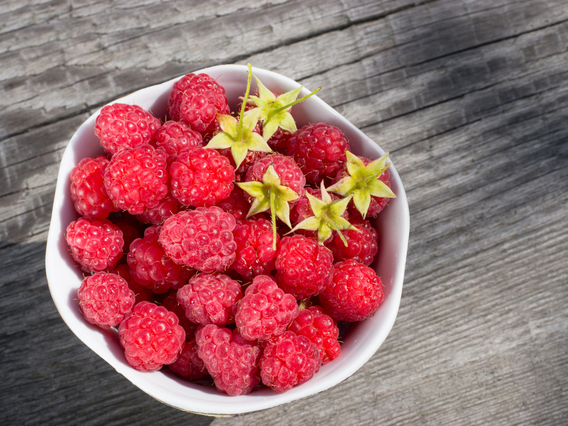 Аппетитная сочная свежая малина в белой тарелке 