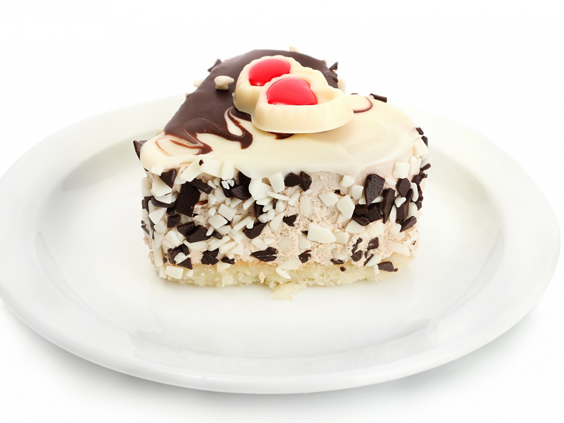 Аппетитное пирожное в форме сердца с шоколадом на белой тарелке