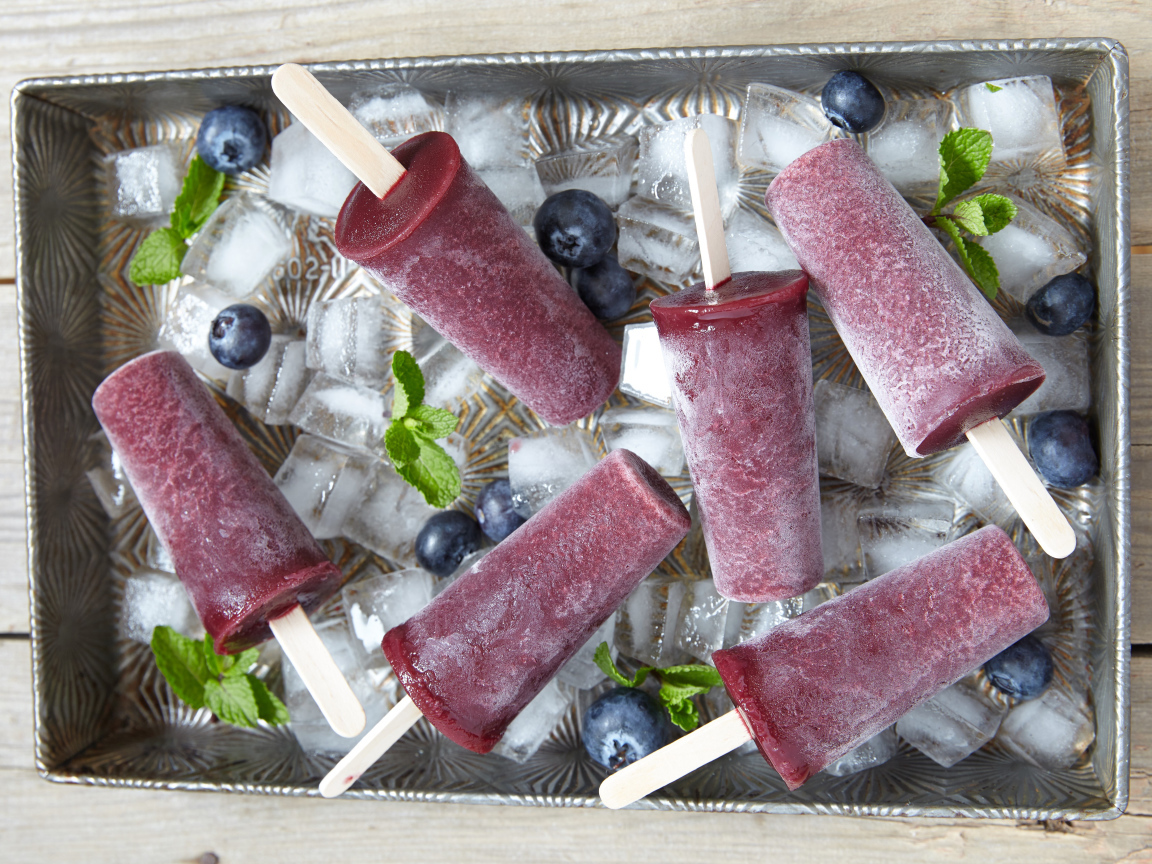 Вкусное черничное мороженое на палочке в лотке со льдом