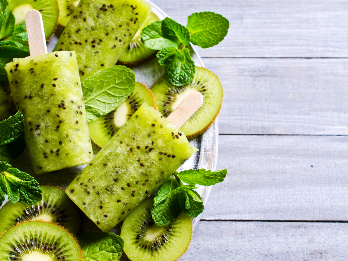 Мороженое с киви и листиками мяты на деревянном столе