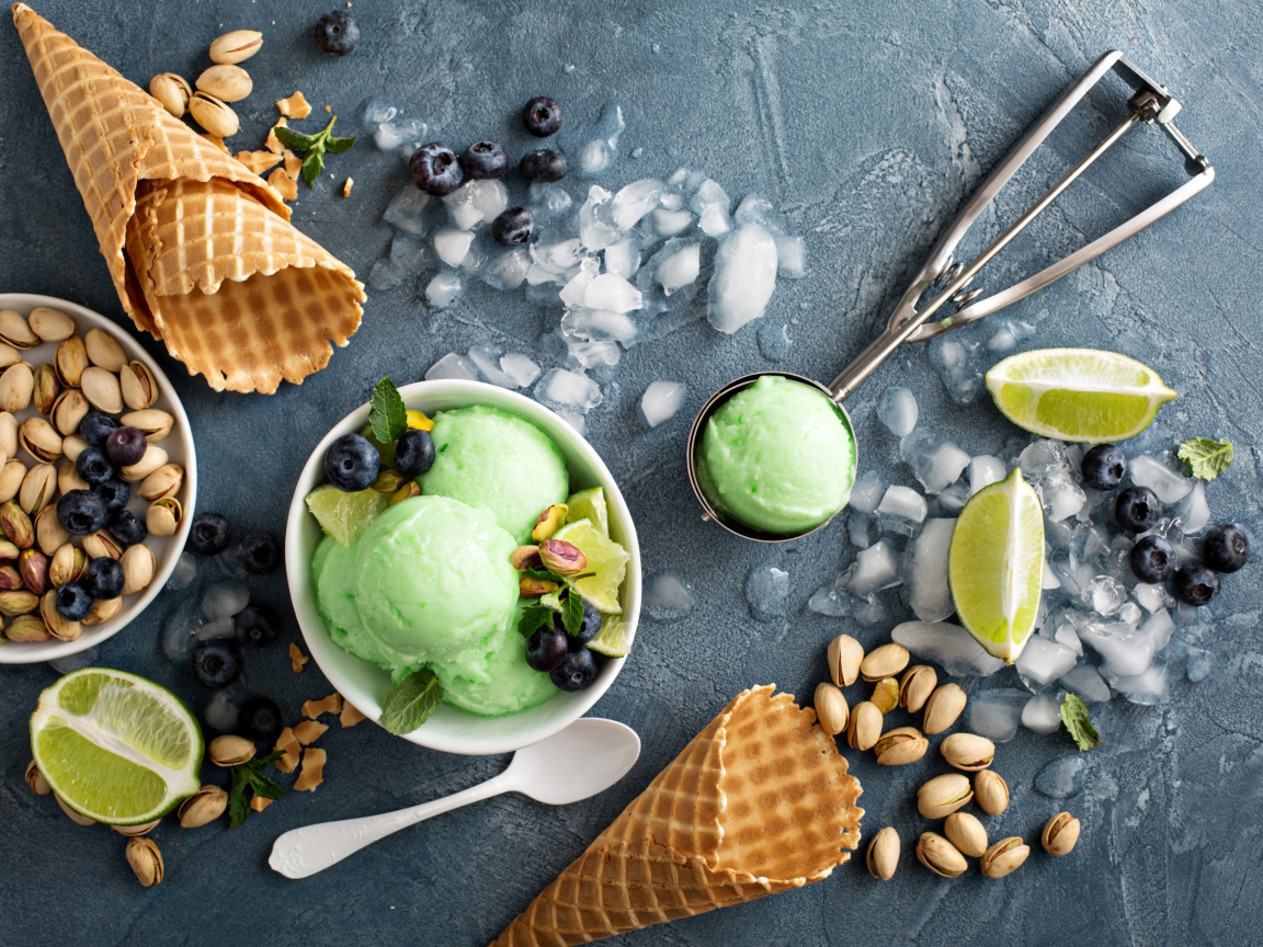 Мороженое с лаймом и фисташками на столе с вафельными рожками и льдом