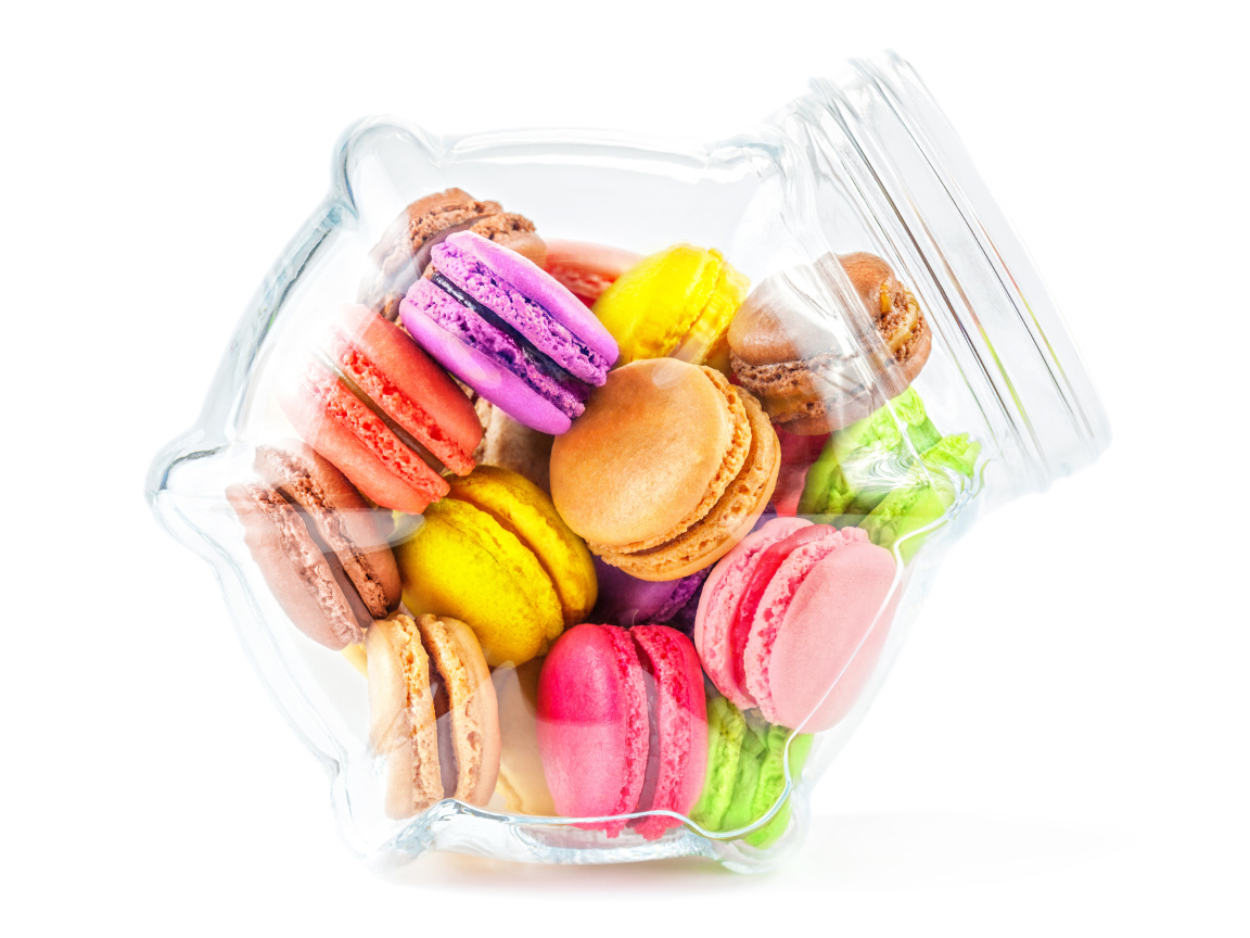 Разноцветные макаруны в стеклянной банке на белом фоне