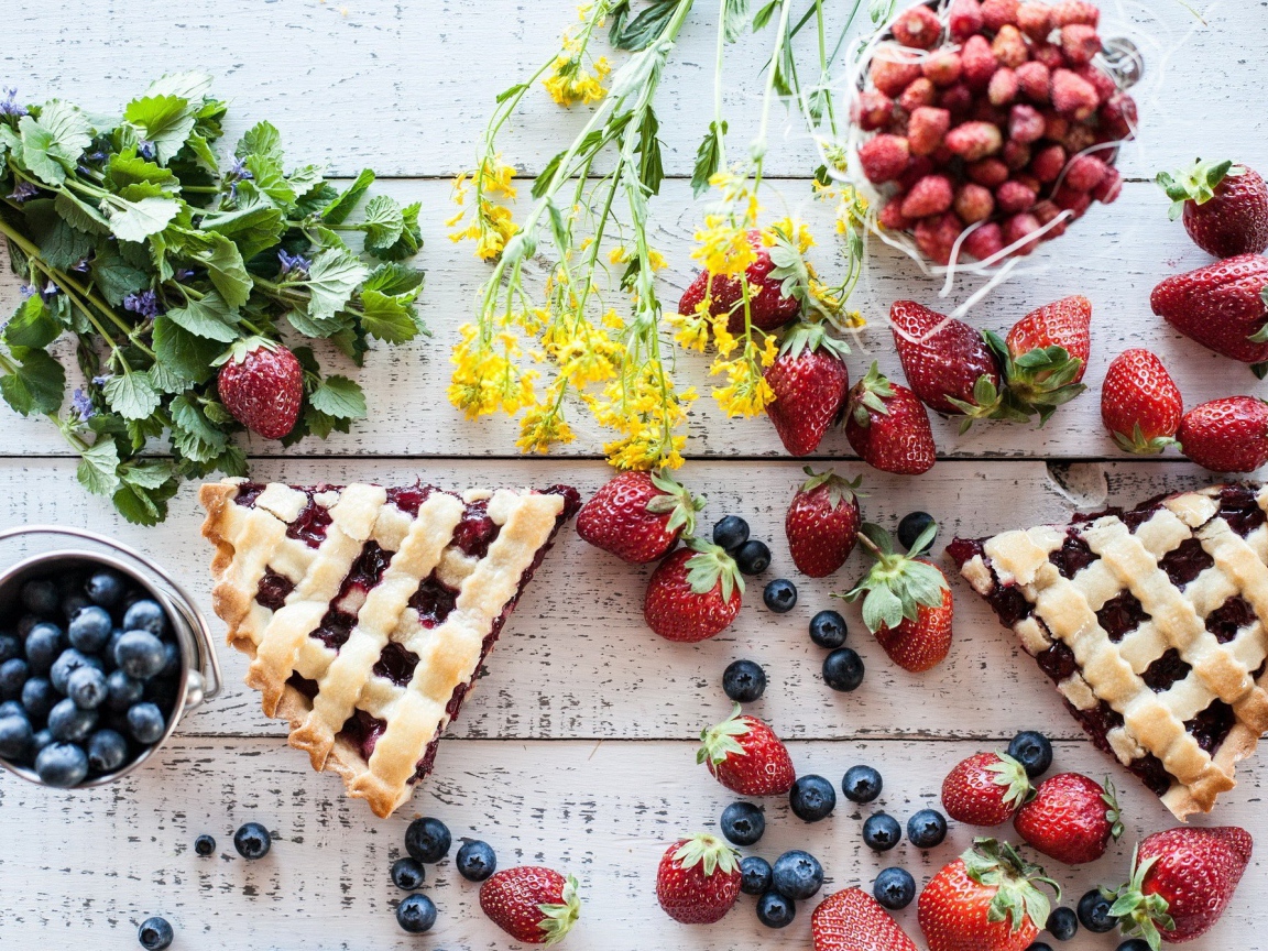 Кусочки пирога на столе с ягодами клубники и черники