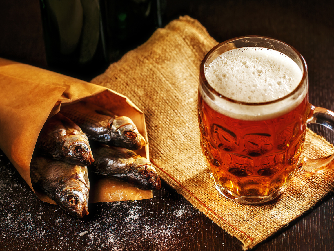 Бокал пива с сушеной рыбой на столе