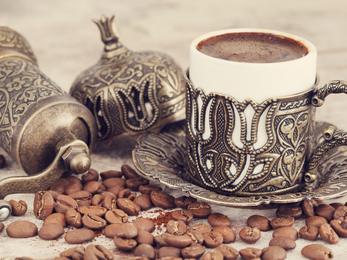 Вкусный кофе в красивой чашке с кофейными зернами на столе