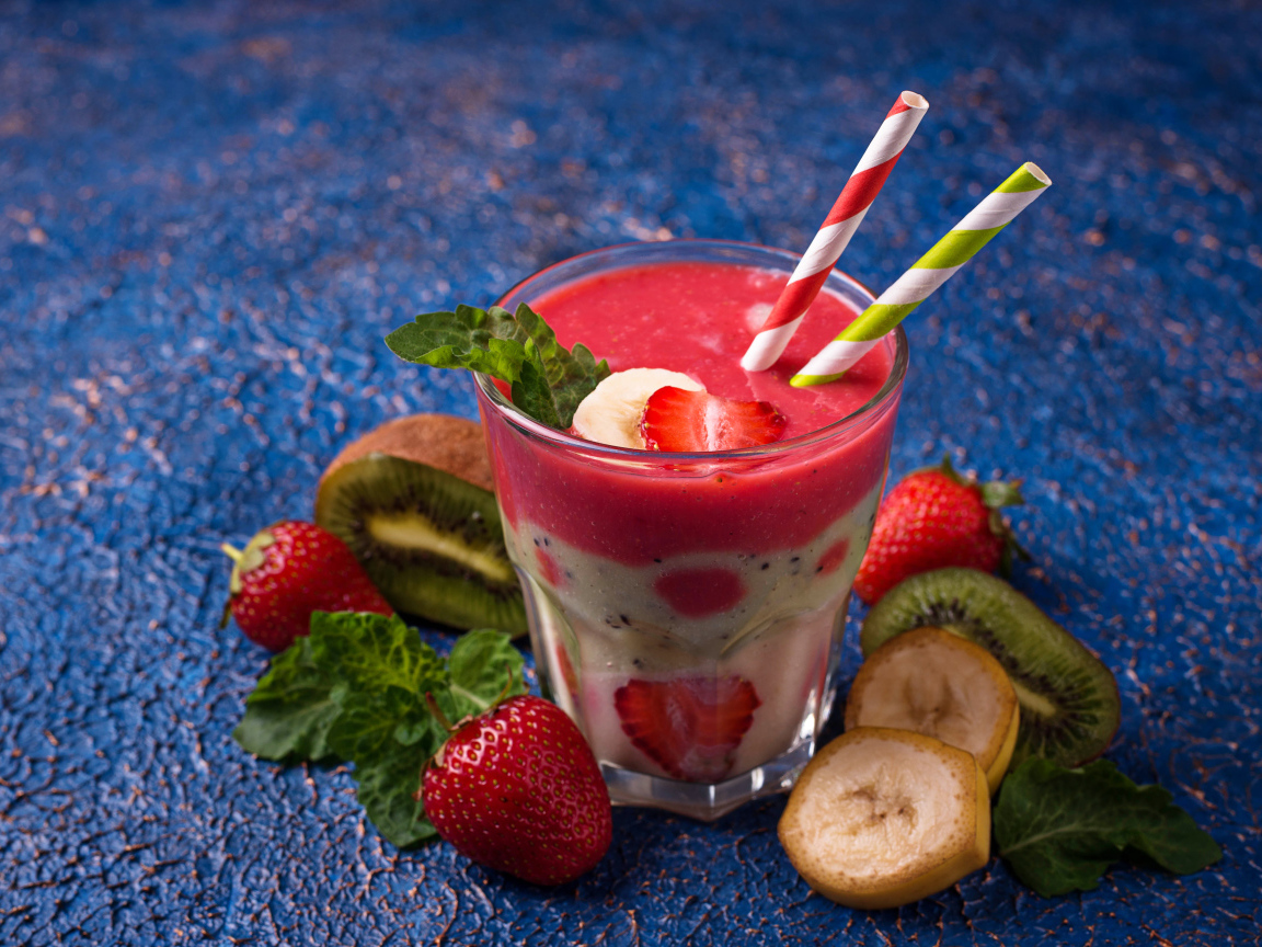 Фруктовый коктейль с клубникой, бананом и киви в стакане с трубочками