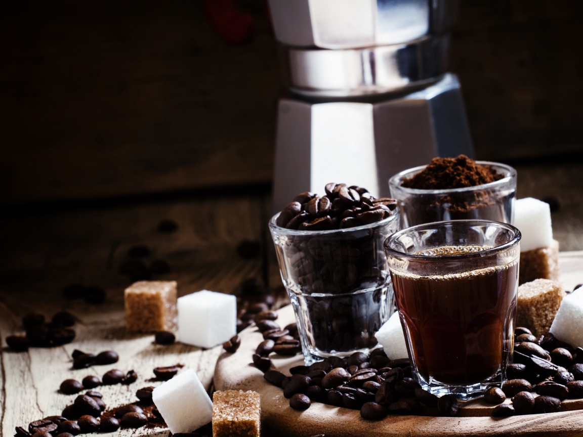 Стаканы с кофе, кофейными зернами и перемолотым кофе на столе с кубиками сахара