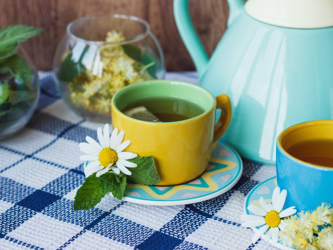 Чай с цветами ромашки в желтой чашке на столе