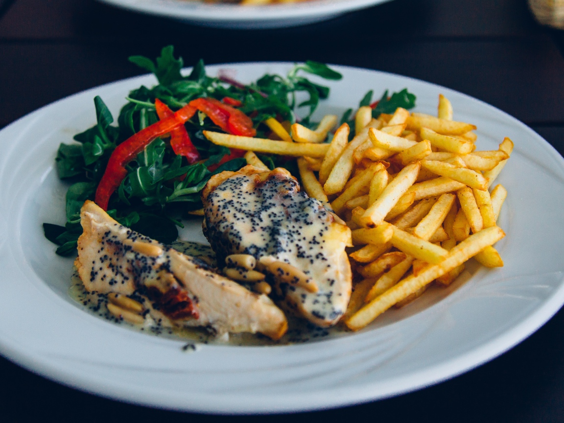 Курица с картофелем фри и салатом на большой белой тарелке