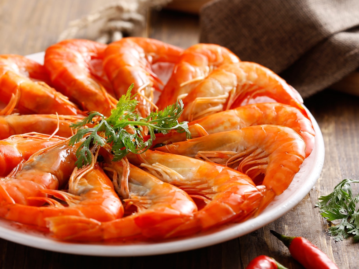 Аппетитные вареные креветки на тарелке с зеленью петрушки