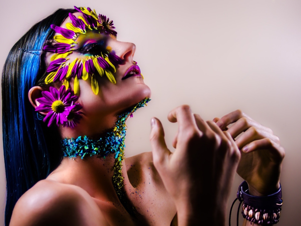 Девушка с украшенным лепестками цветов лицом и ярким макияжем