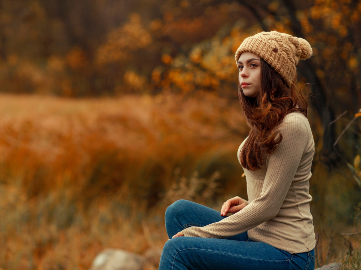 Молодая девушка в синих джинсах и теплой шапке