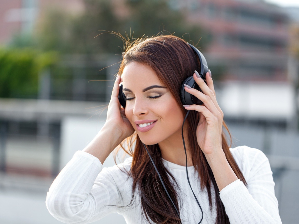 Красивая девушка брюнетка слушает музыку в наушниках 