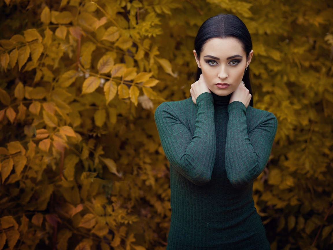 Красивая брюнетка позирует на фоне желтых листьев