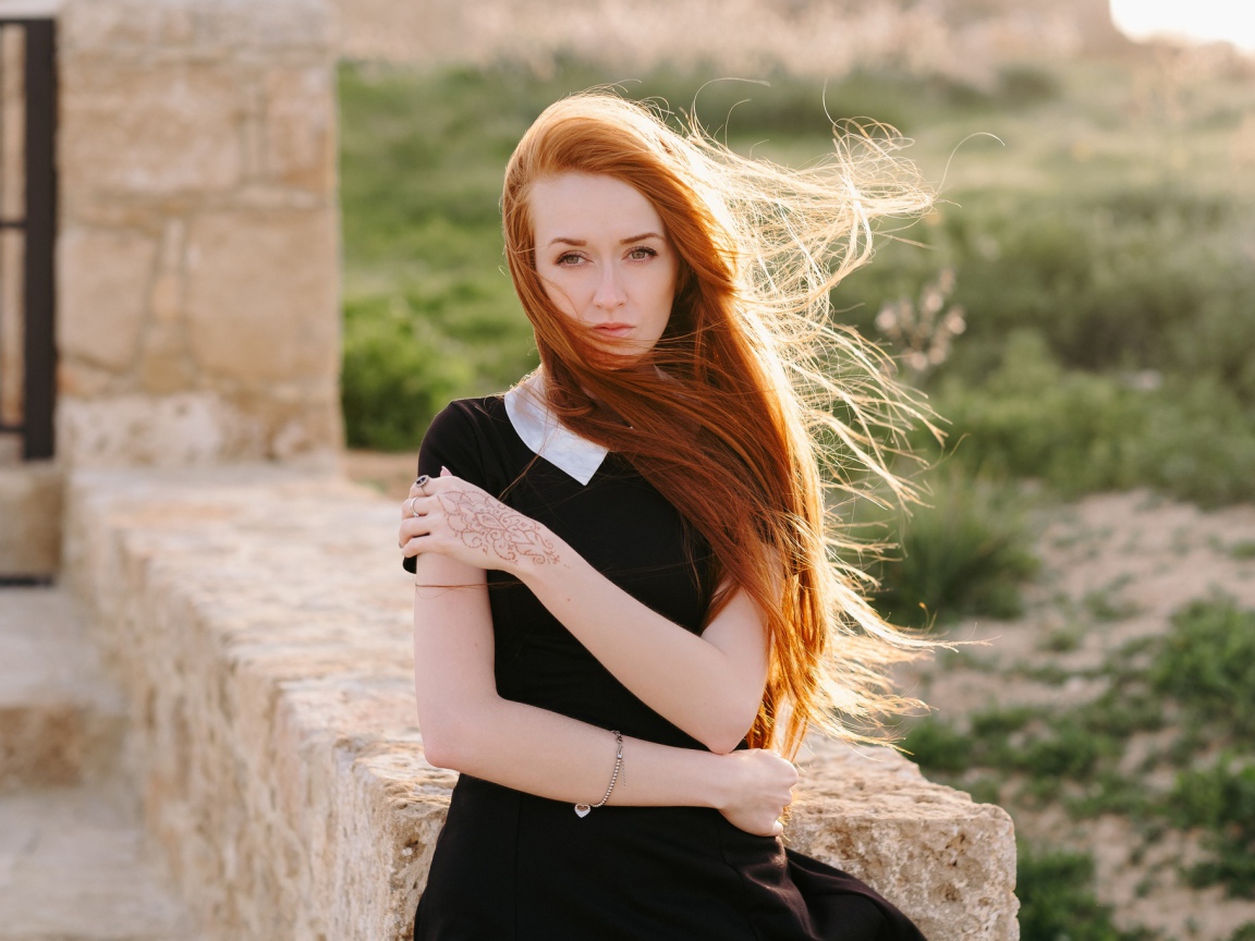 Красивая рыжеволосая девушка в черном платье с рисунком на руке