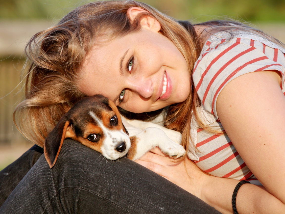 Убающаяся девушка шатенка с милым щенком на руках