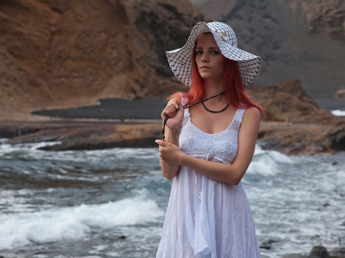 Рыжеволосая девушка в шляпе и белом платье у реки