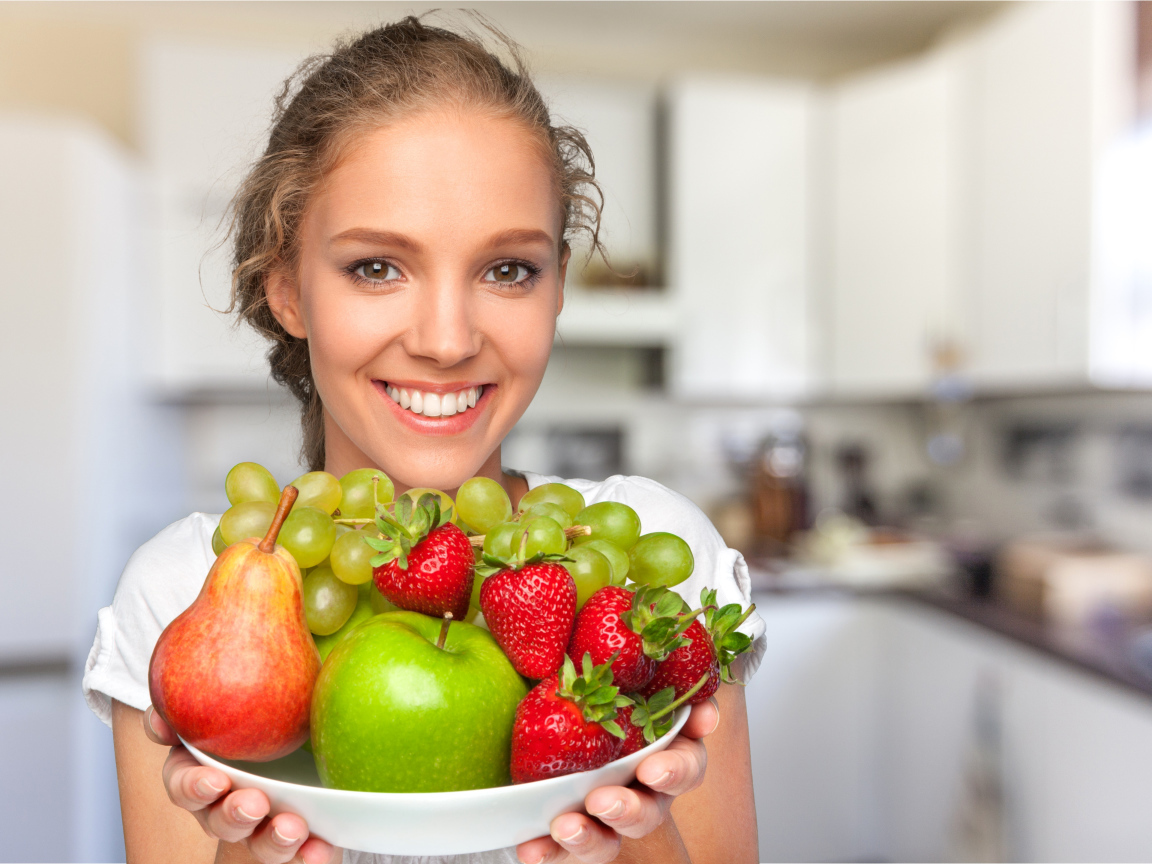 Улыбающаяся девушка со свежими фруктами 