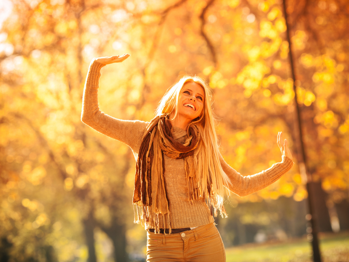 Молодая красивая девушка радуется теплому осеннему солнцу