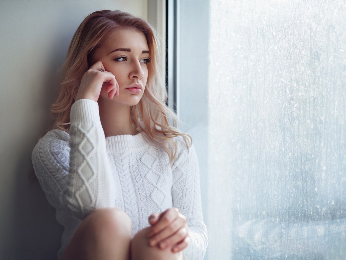 Молодая девушка блондинка у окна 