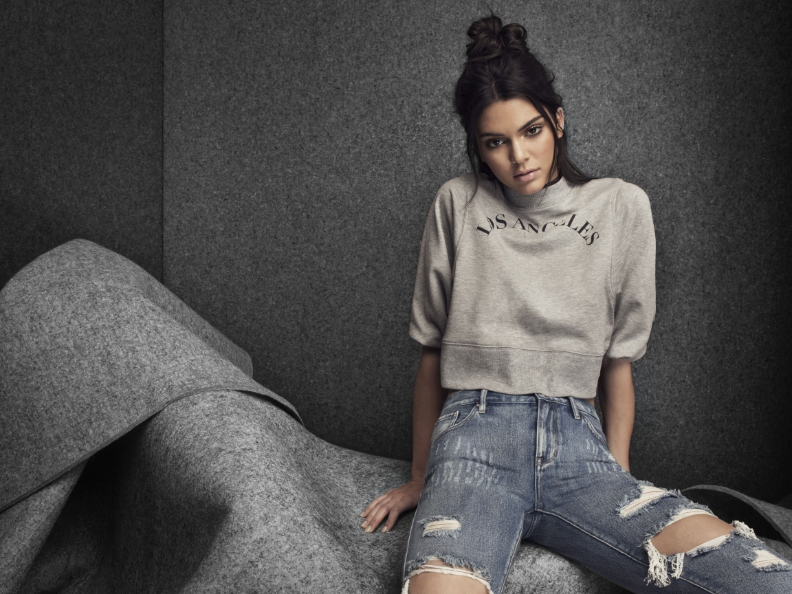 Модель Кендалл Дженнер в рваных джинсах на сером фоне