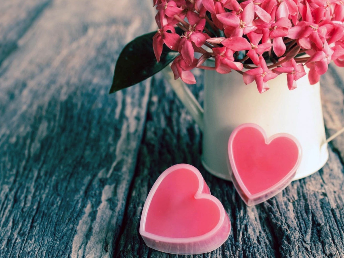 Розовые цветы в белой вазе и два розовых сердца 
