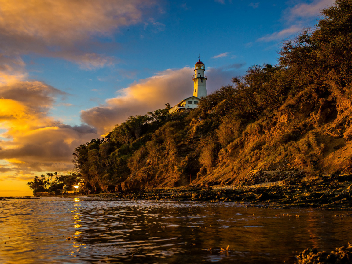 Маяк на склоне скалы на закате 