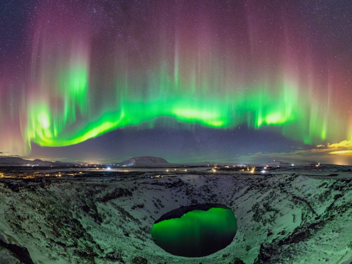 Северное сияние над заснеженным кратером вулкана 