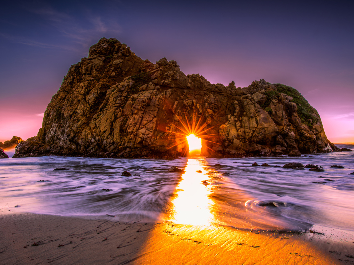 Лучи солнца пробиваются сквозь отверстие в скале  Pfeiffer Beach Big Sur, Калифорния  
