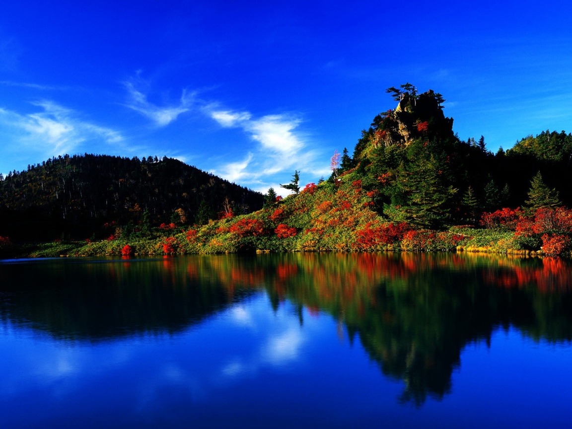 Голубое небо отражается в чистой воде озера 