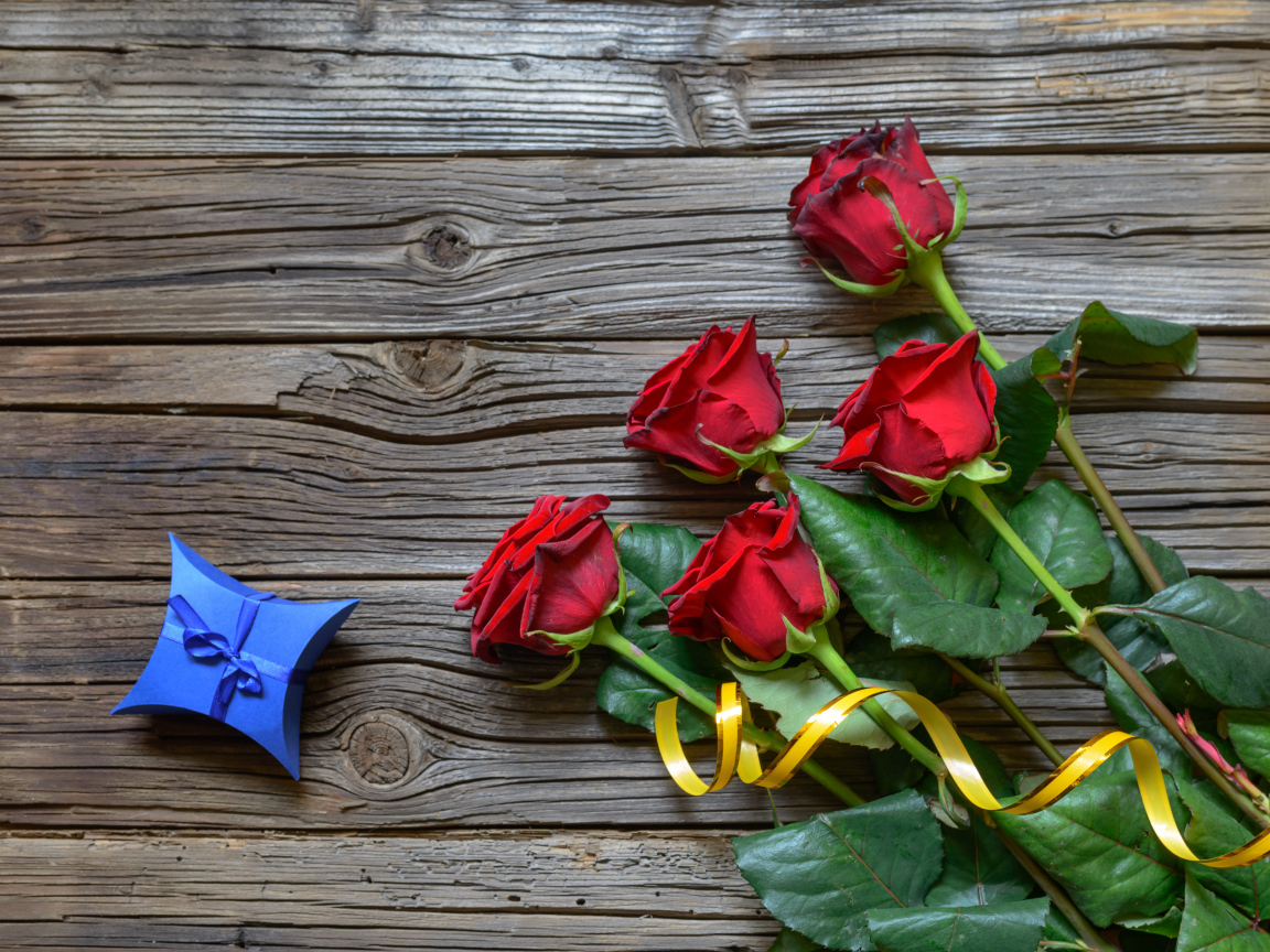 Букет красных роз на столе с синей коробочкой