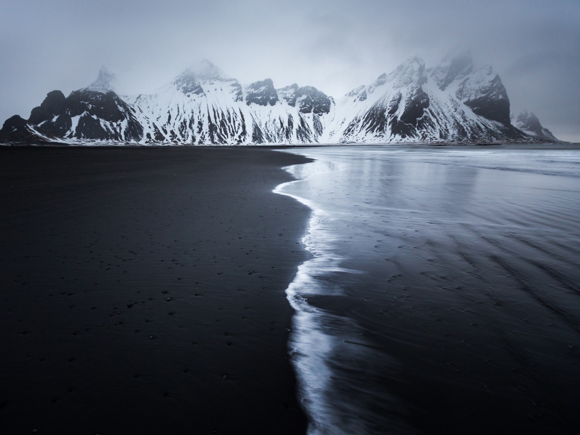 Заснеженные горы у пустынного пляжа