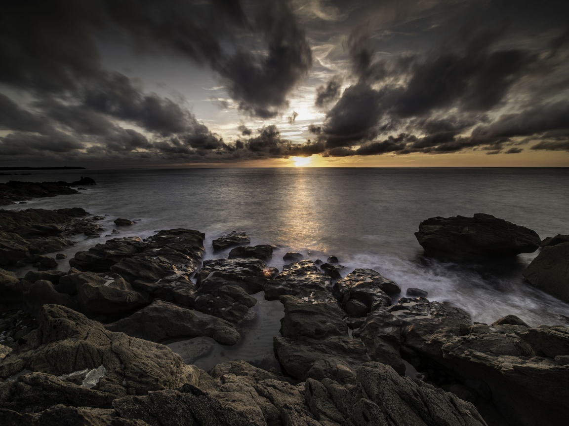 Низкие черные облака на закате в небе над океаном