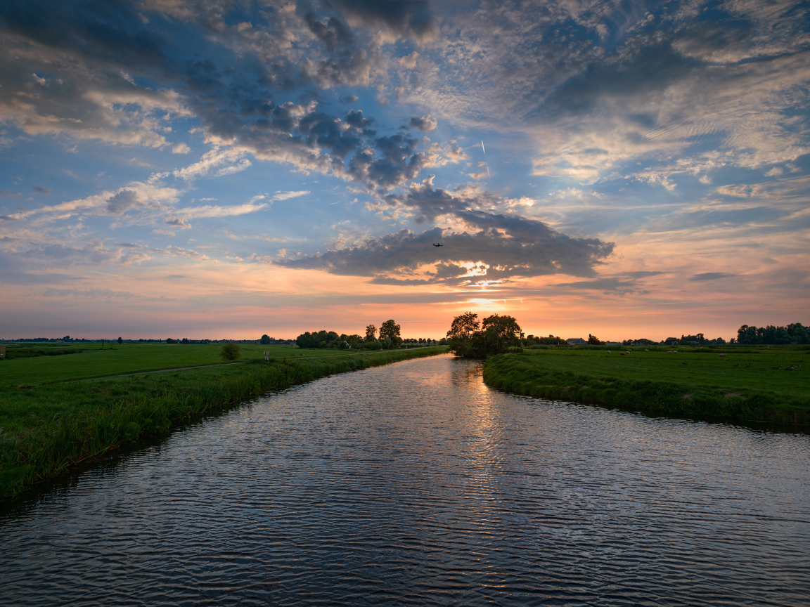 Закат солнца в облаках  над спокойной рекой