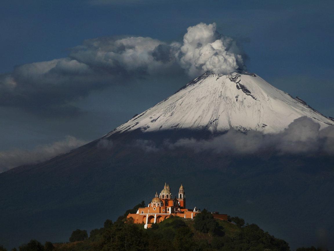 Дымящаяся вершина вулкана Попокатепетль в лучах солнца 