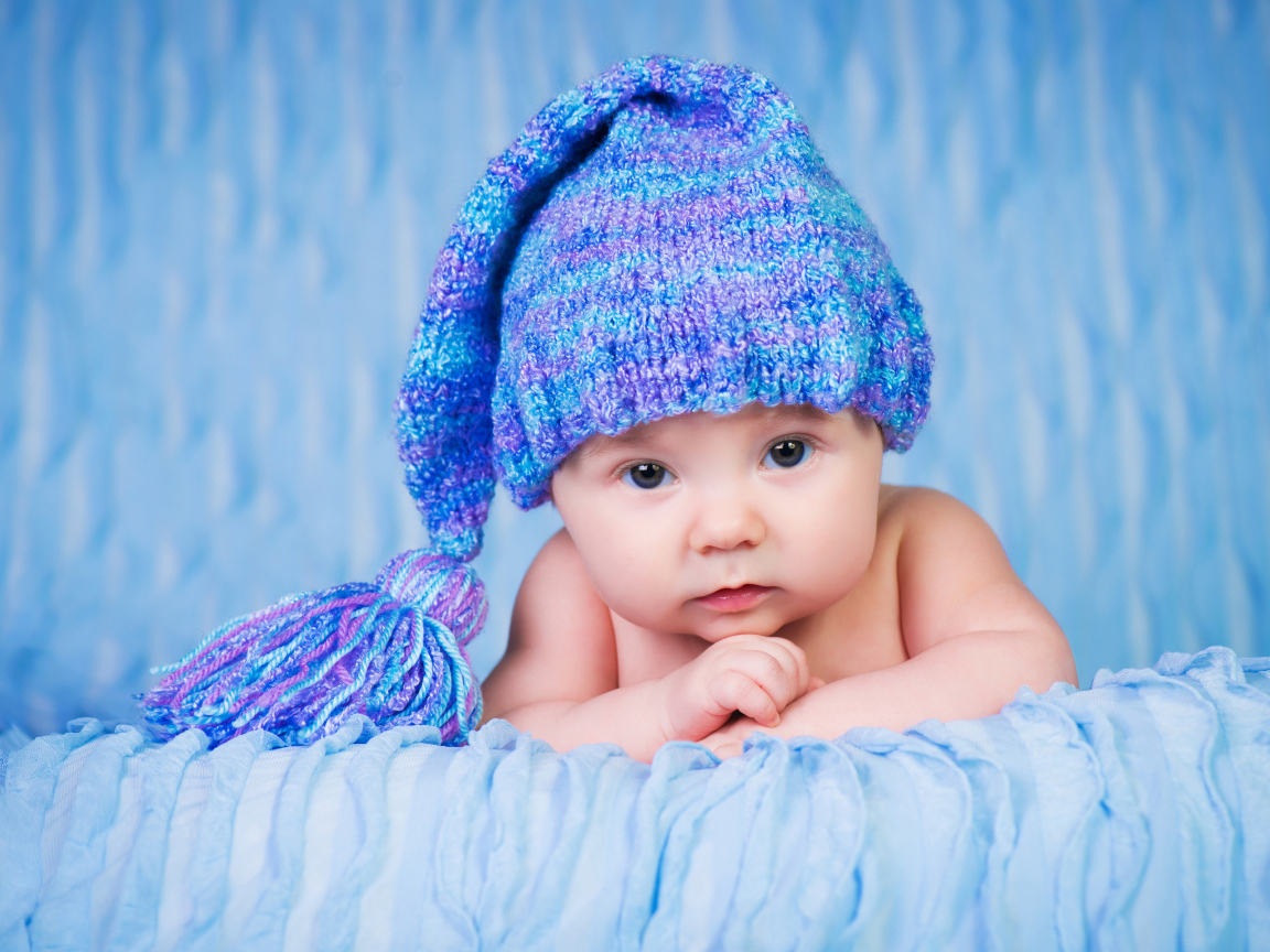 Грудной ребенок в красивой вязаной синей шапке