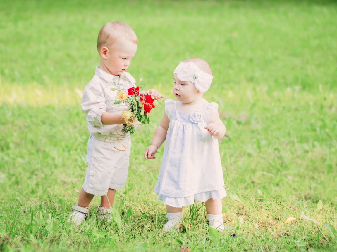 Маленький мальчик дарит букет полевых цветов девочке