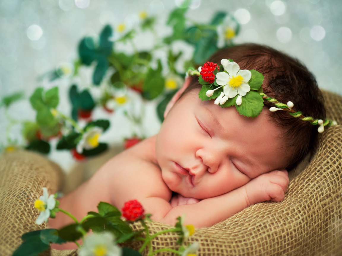 Спящий грудной ребенок с красивой повязкой на голове