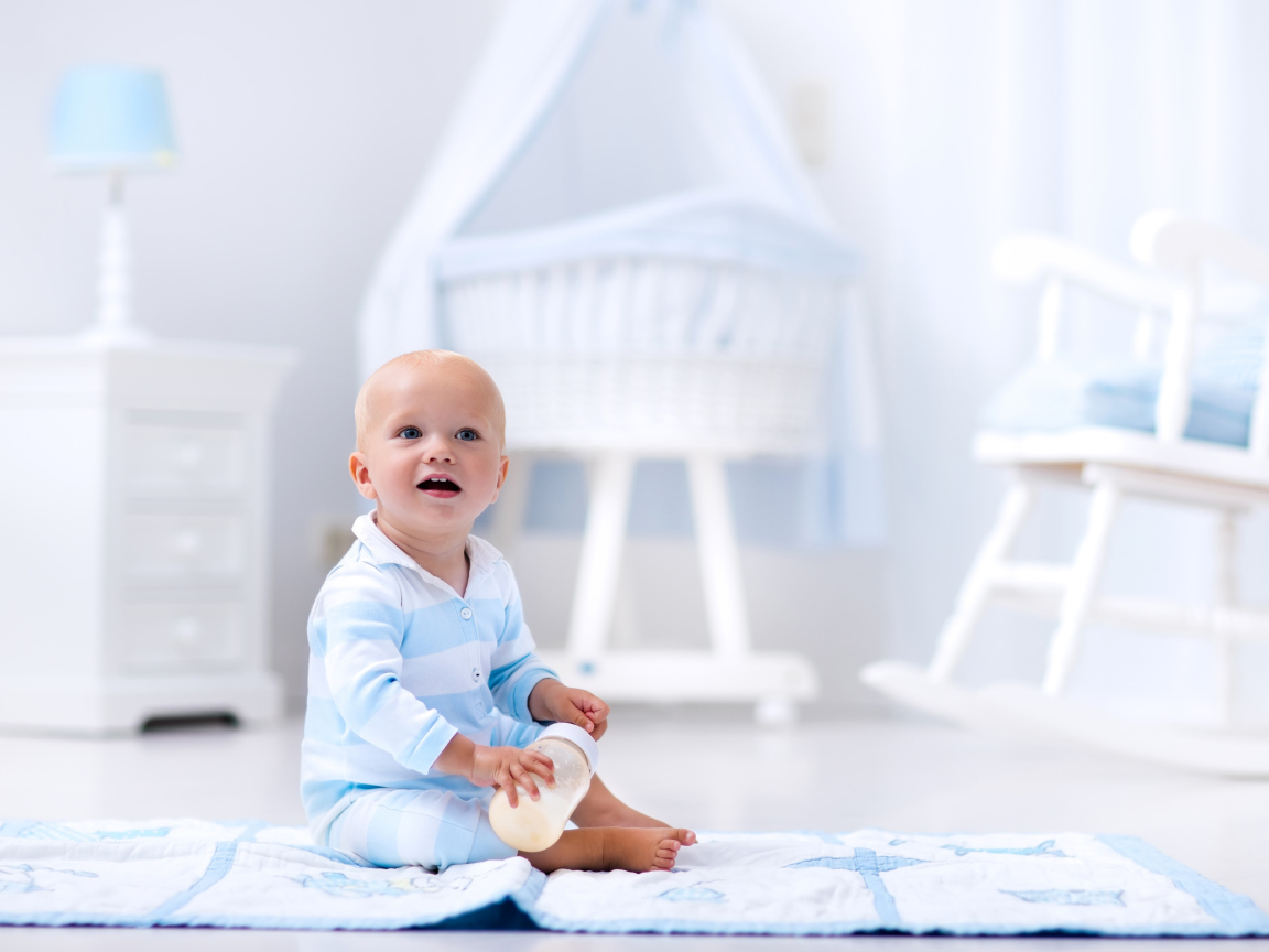 Маленький голубоглазый мальчик сидит на полу в комнате