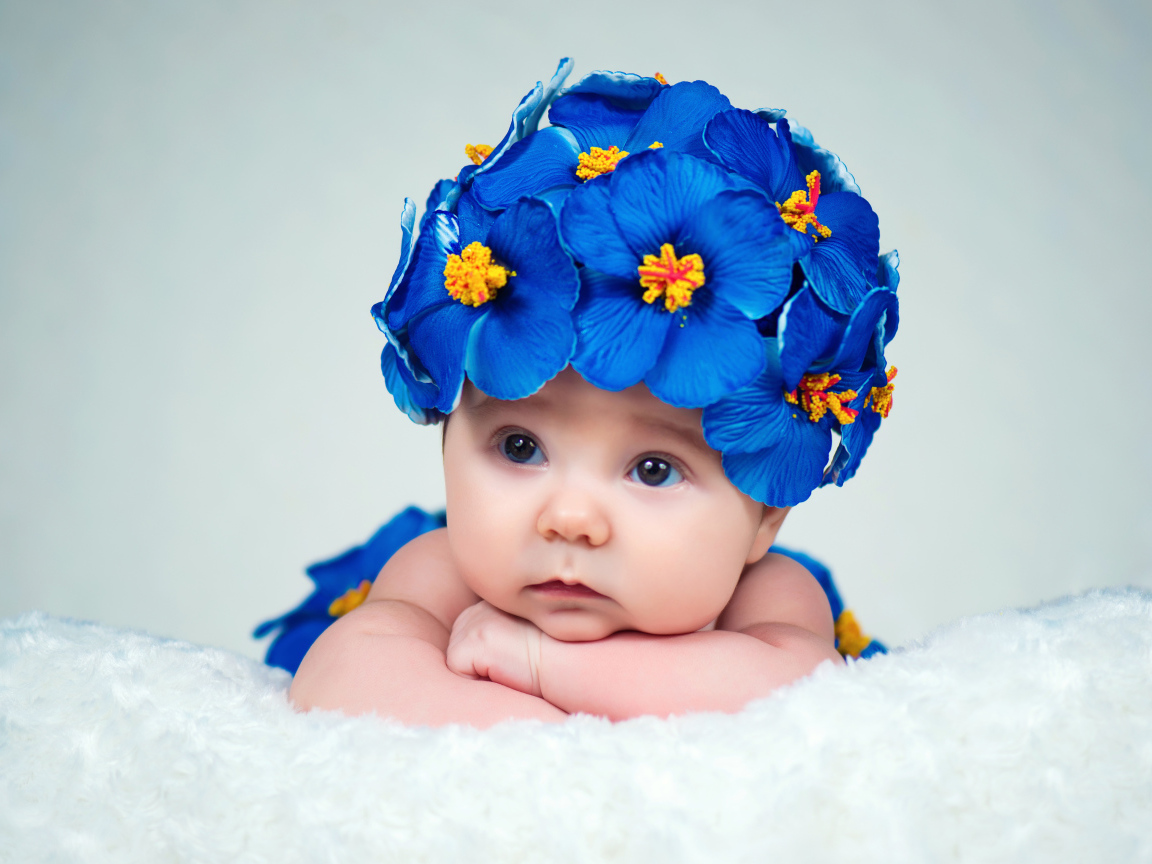 Маленький ребенок в красивой шапке с голубыми цветами
