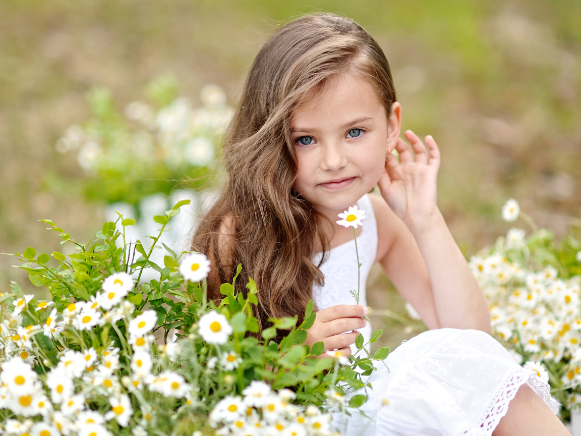 Красивая голубоглазая девочка с белой ромашкой в руке