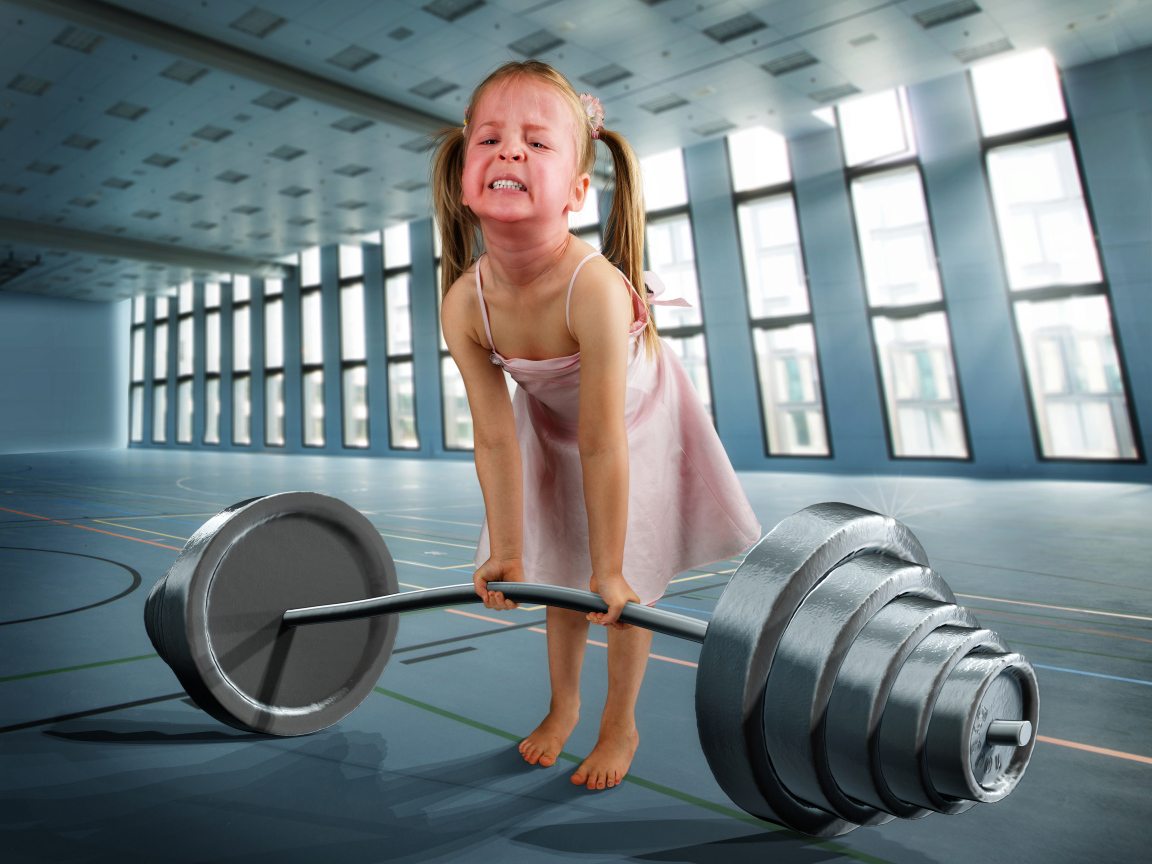Смешная девочка пытается поднять тяжелую штангу